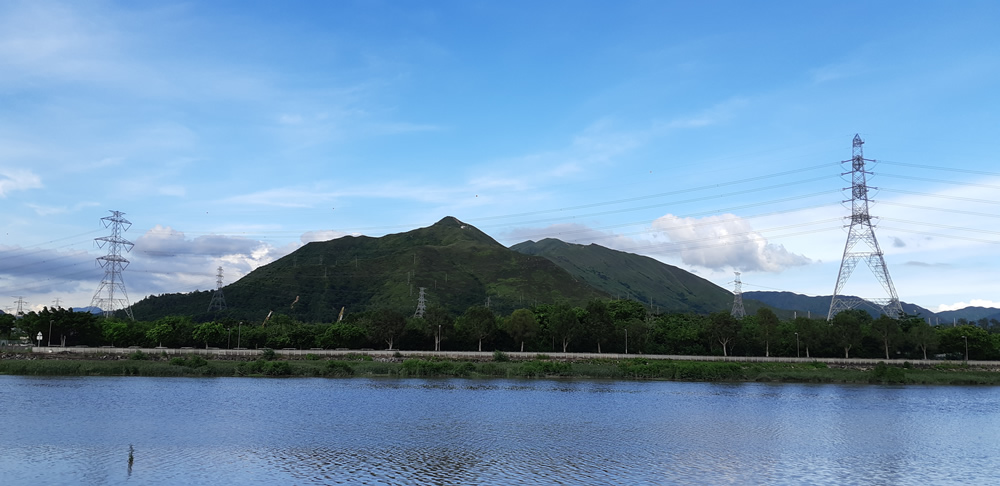 Scenery of country pond and transmission tower under blue sky